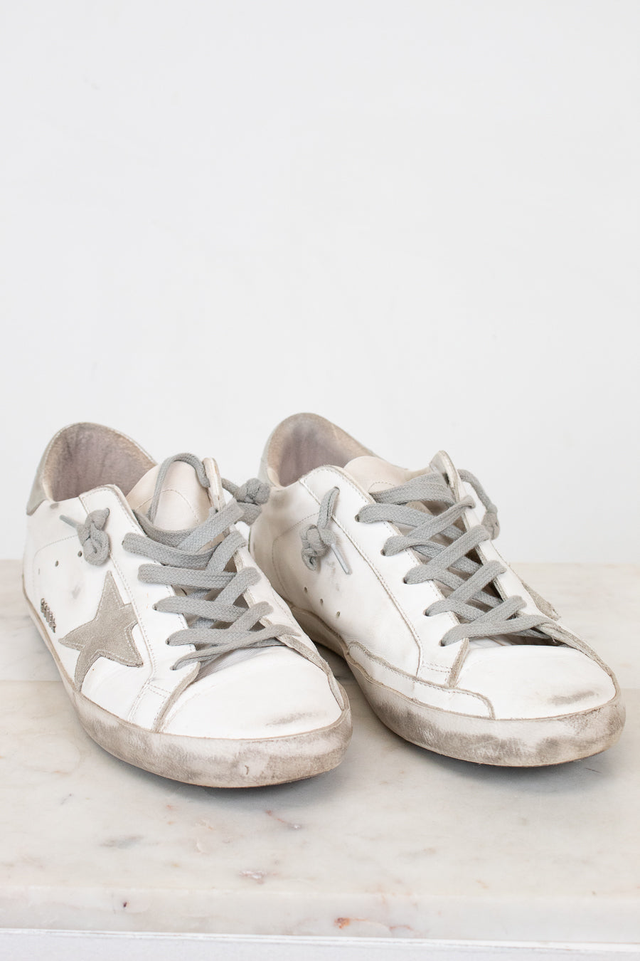 Pair of white sneakers with gray soles on a light background