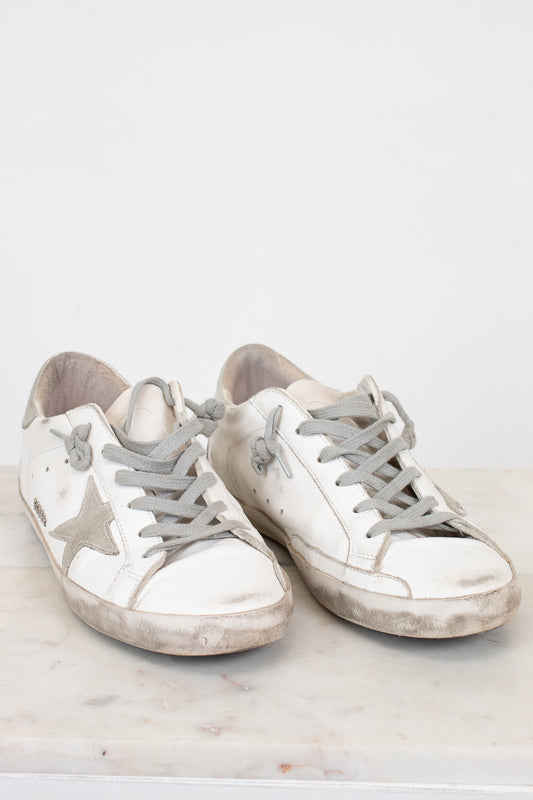 Pair of white sneakers with gray soles on a light background