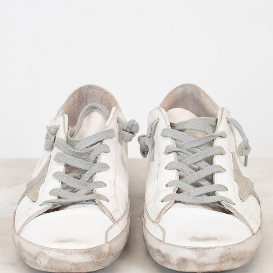 Pair of white sneakers with gray laces on a light background