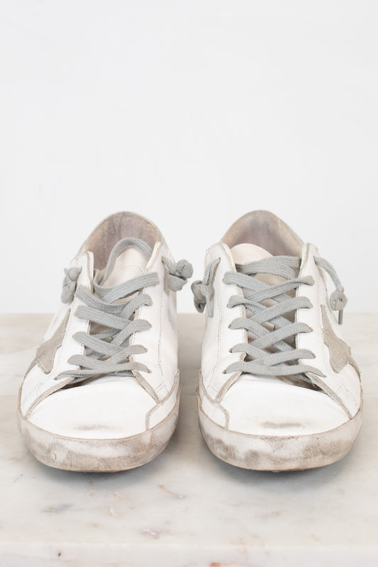 Pair of white sneakers with gray laces on a light background
