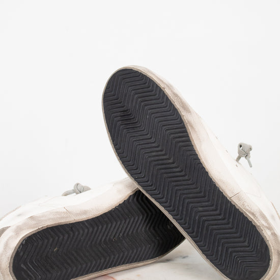 Close-up of white sneakers with black soles on a light background
