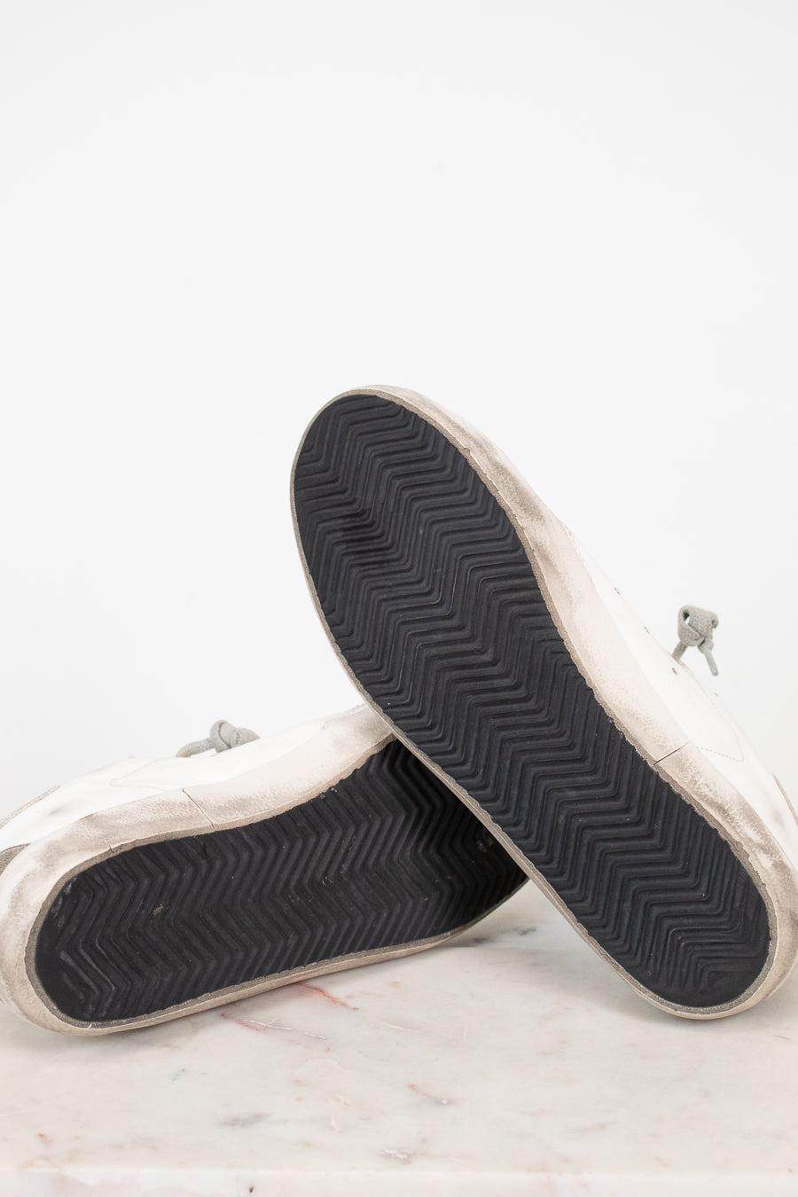 Close-up of white sneakers with black soles on a light background