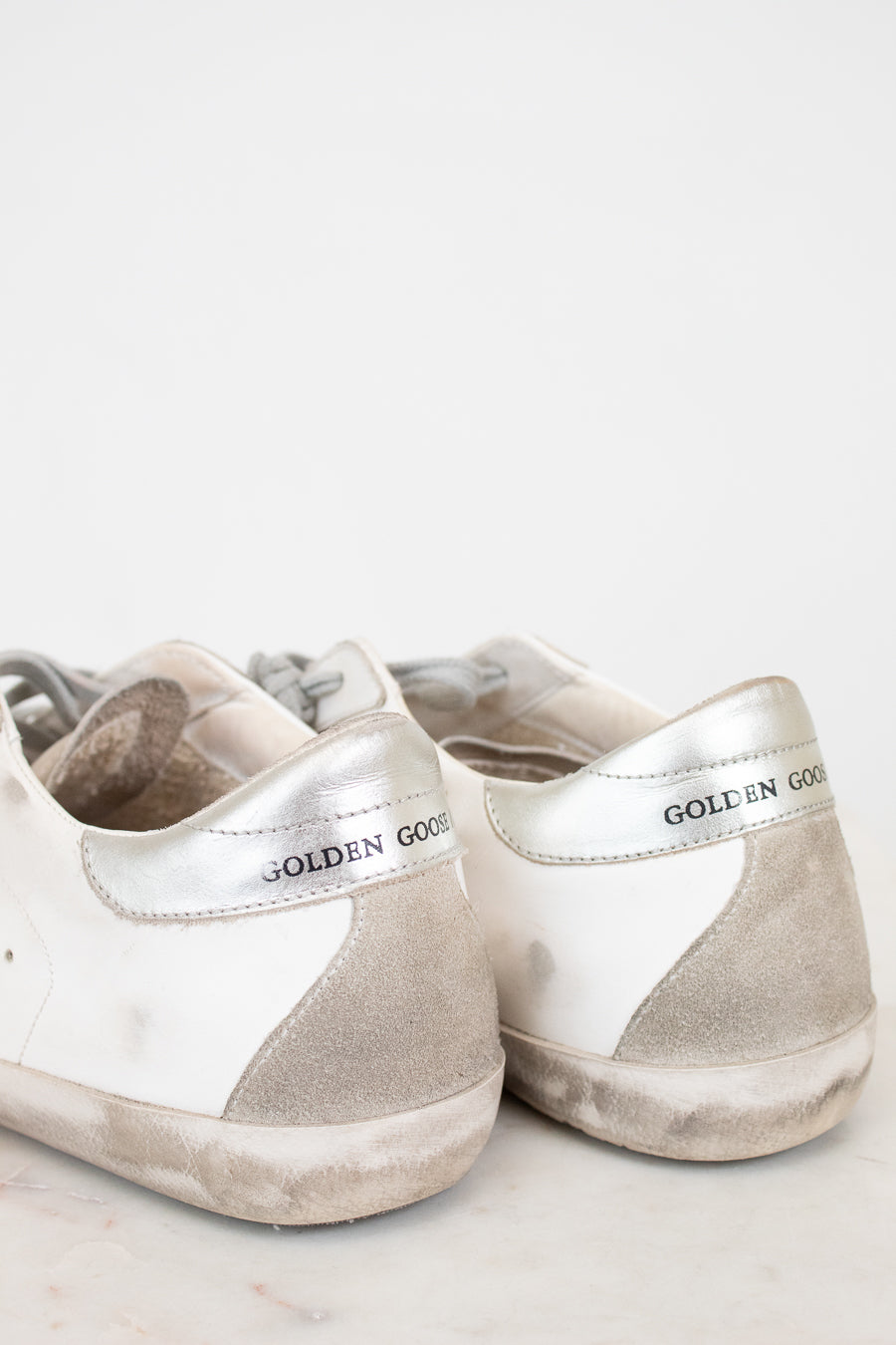 Pair of white and gray sneakers with 'Golden Goose' branding on a light background
