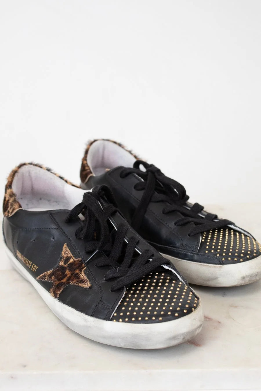 Black sneakers with gold star and dot patterns on a light background
