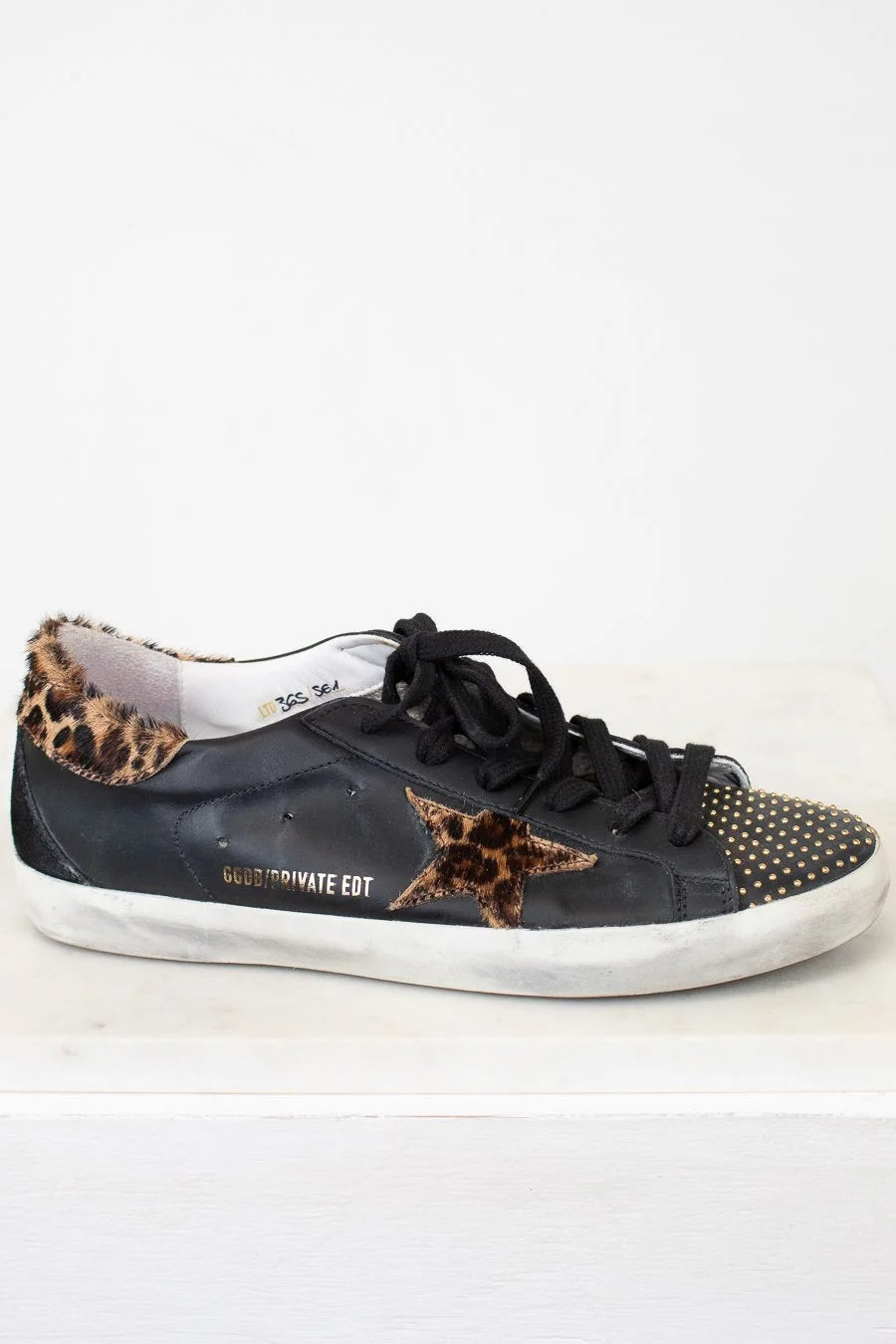 Black sneaker with leopard print accents on a white background