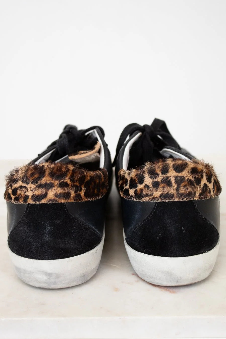Black sneakers with leopard print accents on a light background