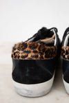 Black sneakers with leopard print accents on a light background