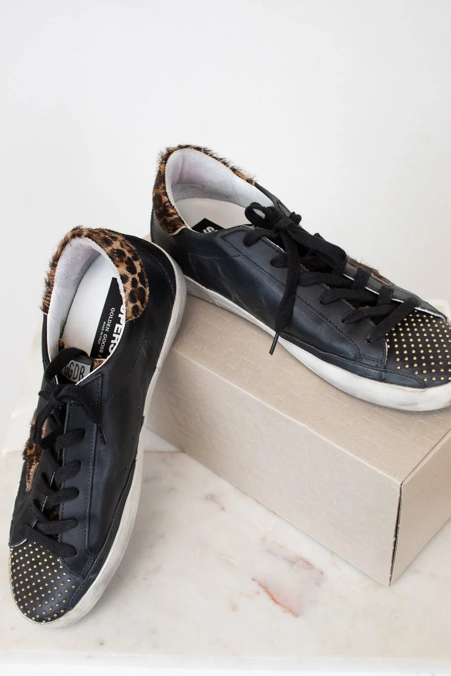 Black sneakers with leopard print accents on a white surface