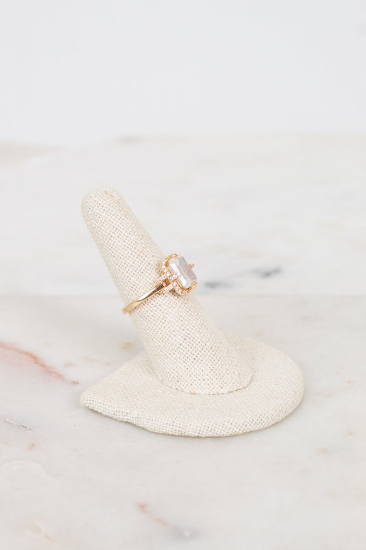Gold ring with a large moon quartz on a white marble surface