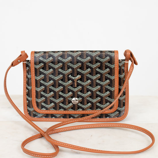 Designer handbag with a patterned flap and brown strap on a white background