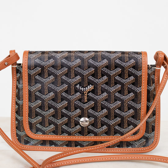 Patterned handbag with brown leather strap on a white background