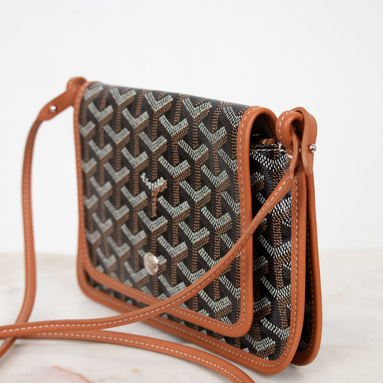 Patterned handbag with brown leather strap on a white background