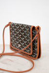 Patterned handbag with brown leather strap on a white background