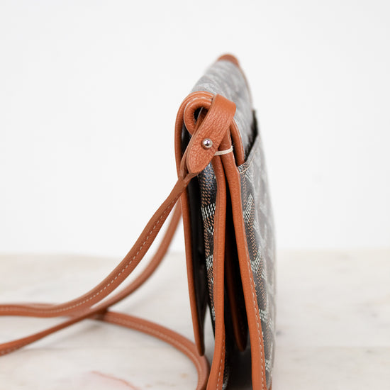 Small crossbody bag with brown strap on a marble surface