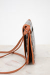 Small crossbody bag with brown strap on a marble surface