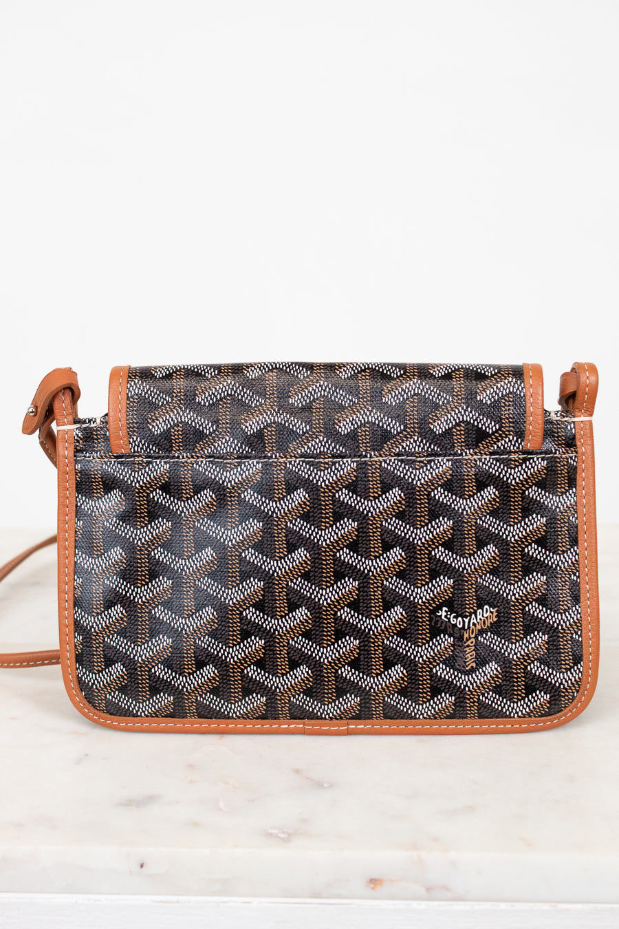 Patterned handbag with brown leather straps on a white background