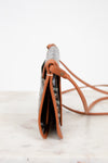 Small handbag with a patterned flap and brown leather strap on a light background