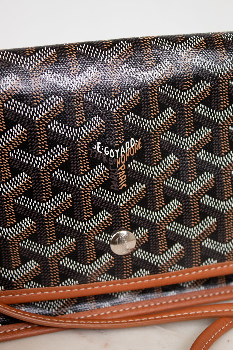 Designer handbag with a distinctive pattern and brand logo on a light background