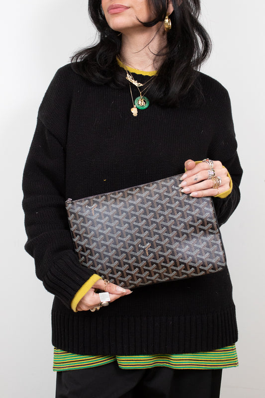 Person holding a patterned clutch against a plain background