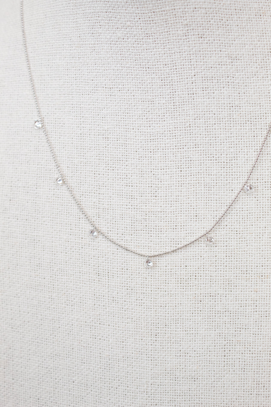White gold diamond necklace on a fabric surface