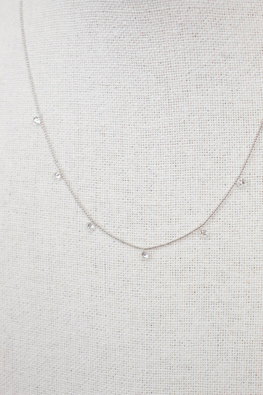 White gold diamond necklace on a fabric surface