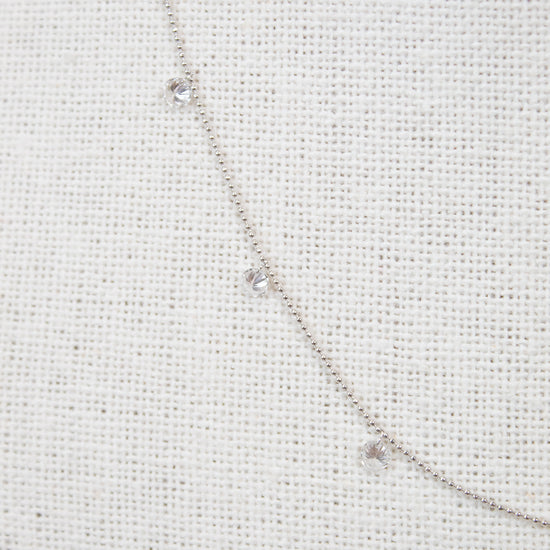 White gold diamond necklace on a fabric surface