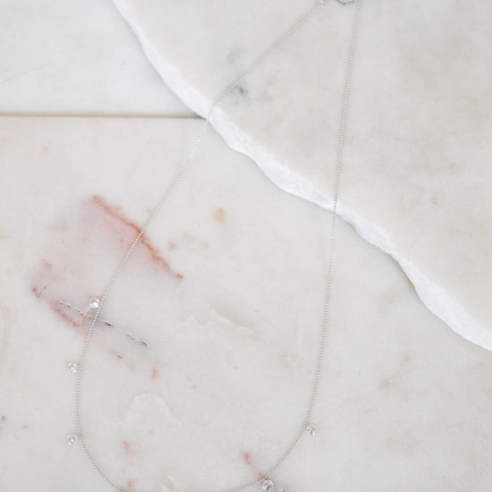 Necklace with small diamond pendants on a marble surface