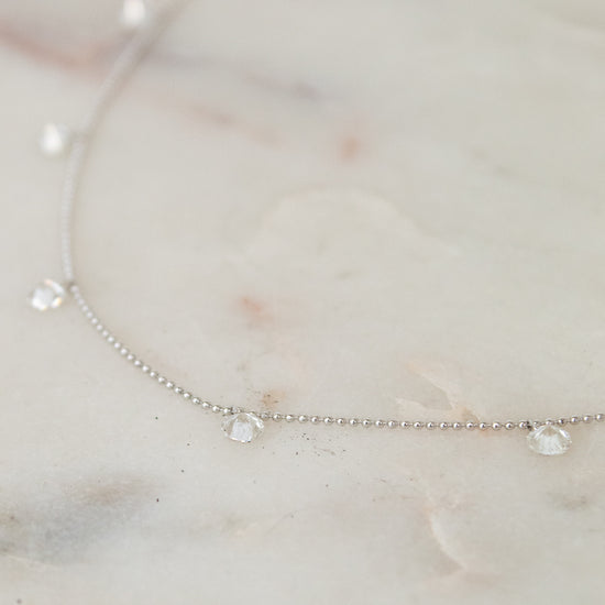 White gold diamond necklace on a marble surface