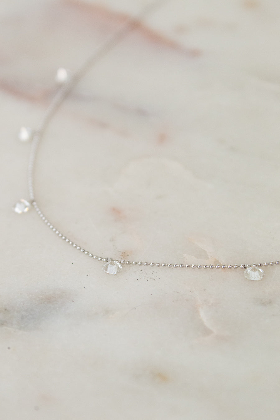 White gold diamond necklace on a marble surface