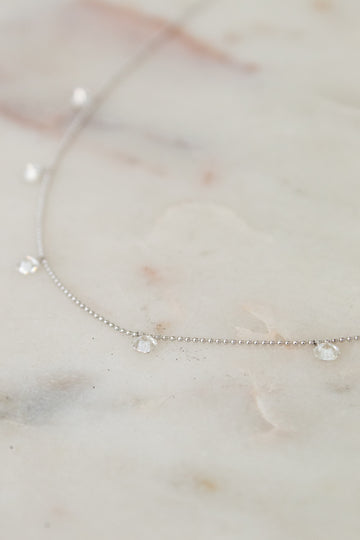 White gold diamond necklace on a marble surface