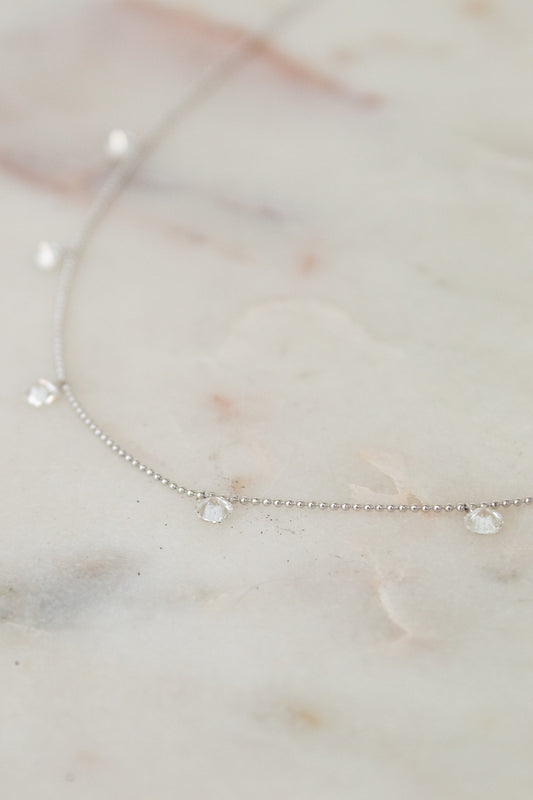 White gold diamond necklace on a marble surface