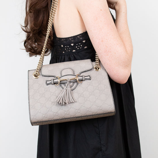 Woman holding a gray handbag with a tassel detail against a white background