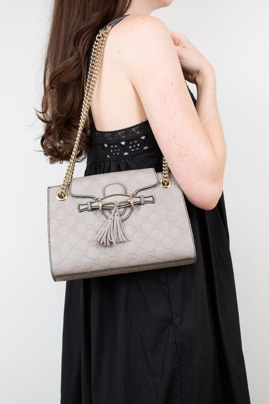 Woman holding a gray handbag with a tassel detail against a white background