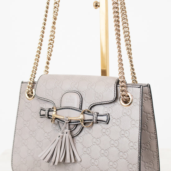 Grey handbag with chain strap and tassel on a white background
