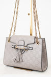 Grey handbag with chain strap and tassel on a white background