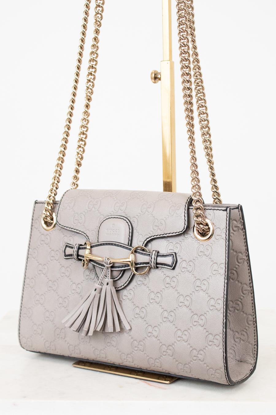 Grey handbag with chain strap and tassel on a white background