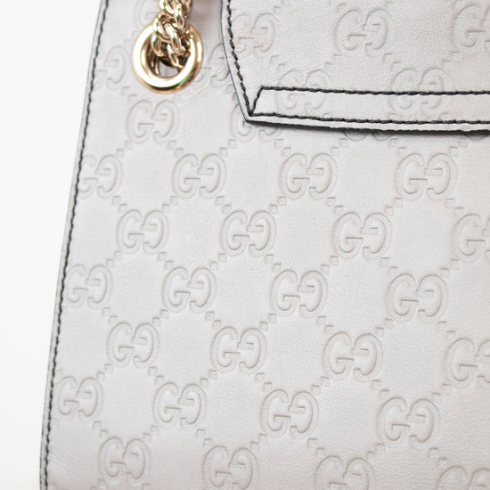 Grey Gucci handbag with gold chain strap on a white background