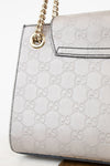 Grey Gucci handbag with gold chain strap on a white background