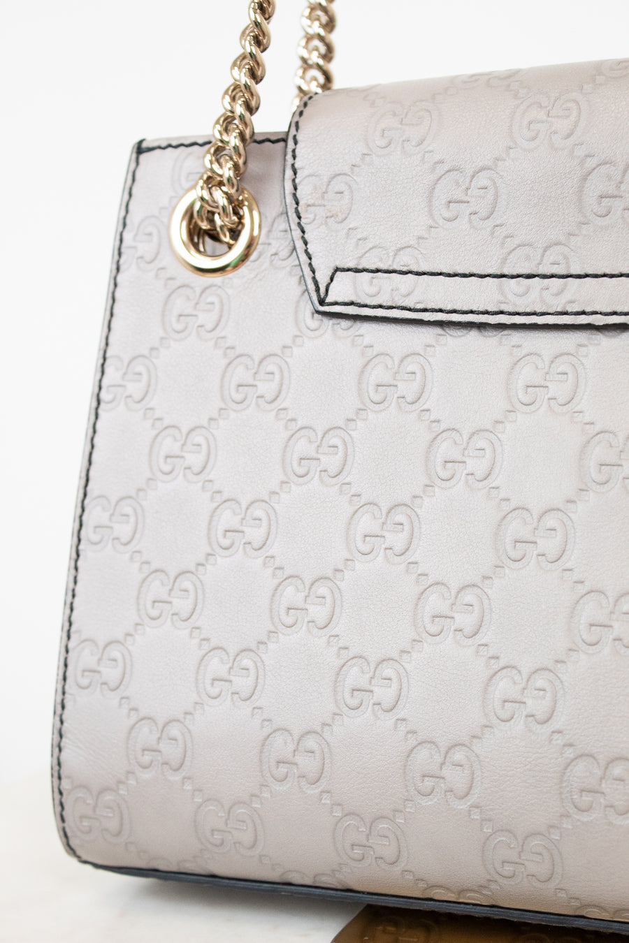 Grey Gucci handbag with gold chain strap on a white background