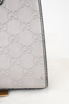 Close-up of a Gucci handbag with signature logo pattern on a white background