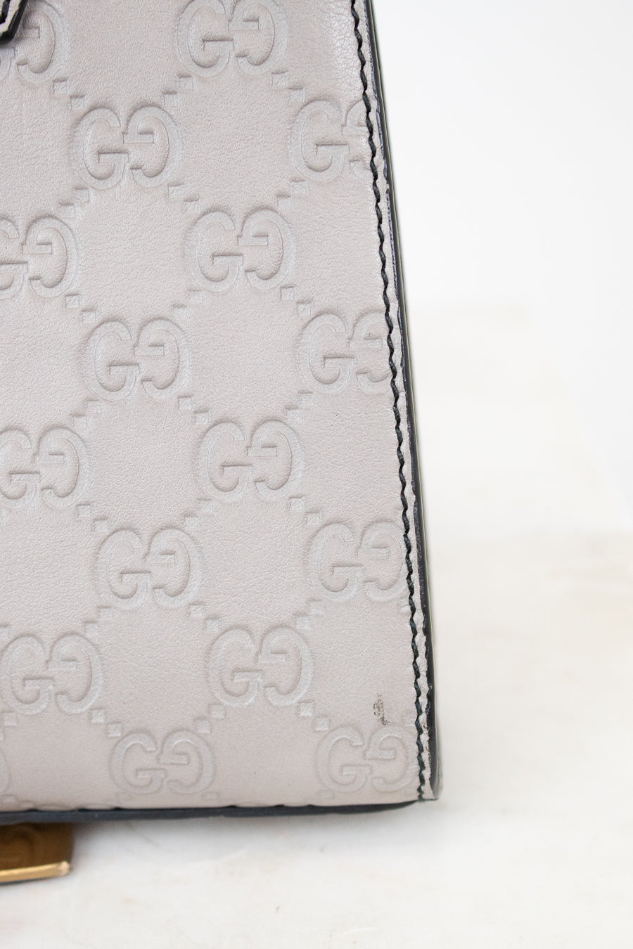 Close-up of a Gucci handbag with signature logo pattern on a white background
