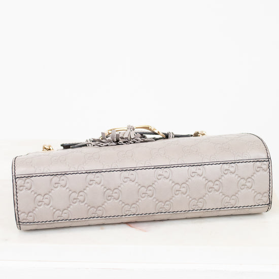 Light gray Gucci handbag with a decorative clasp on a white background