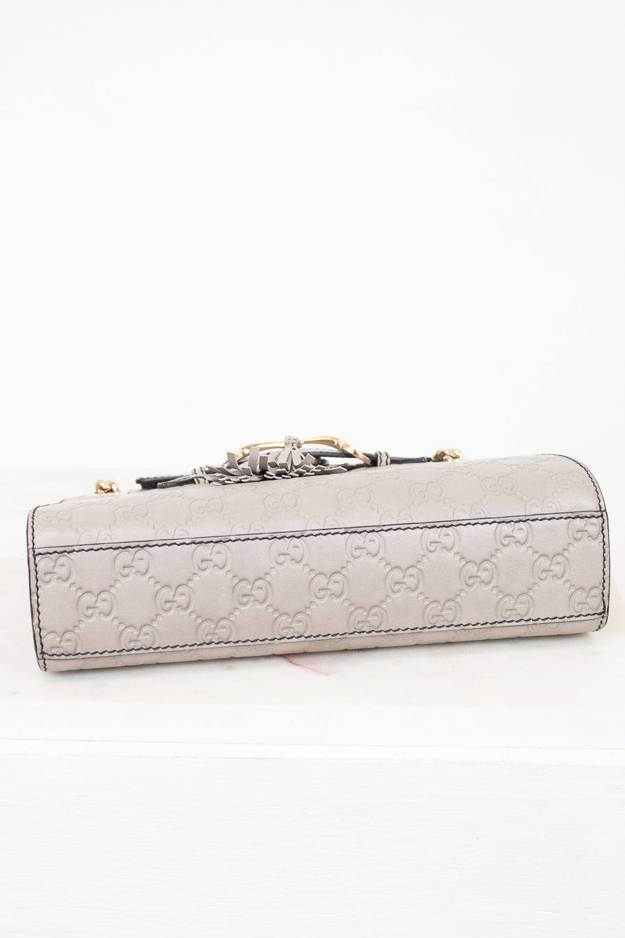 Light gray Gucci handbag with a decorative clasp on a white background