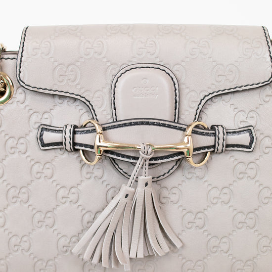 Light gray handbag with Gucci logo and tassel detail on a white background