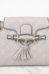 Light gray handbag with Gucci logo and tassel detail on a white background
