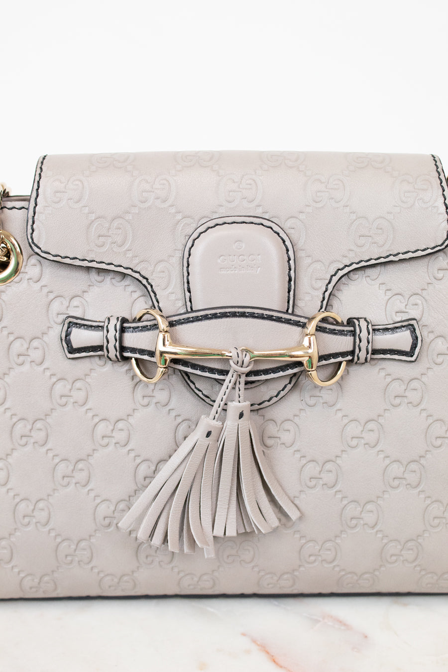 Light gray handbag with Gucci logo and tassel detail on a white background