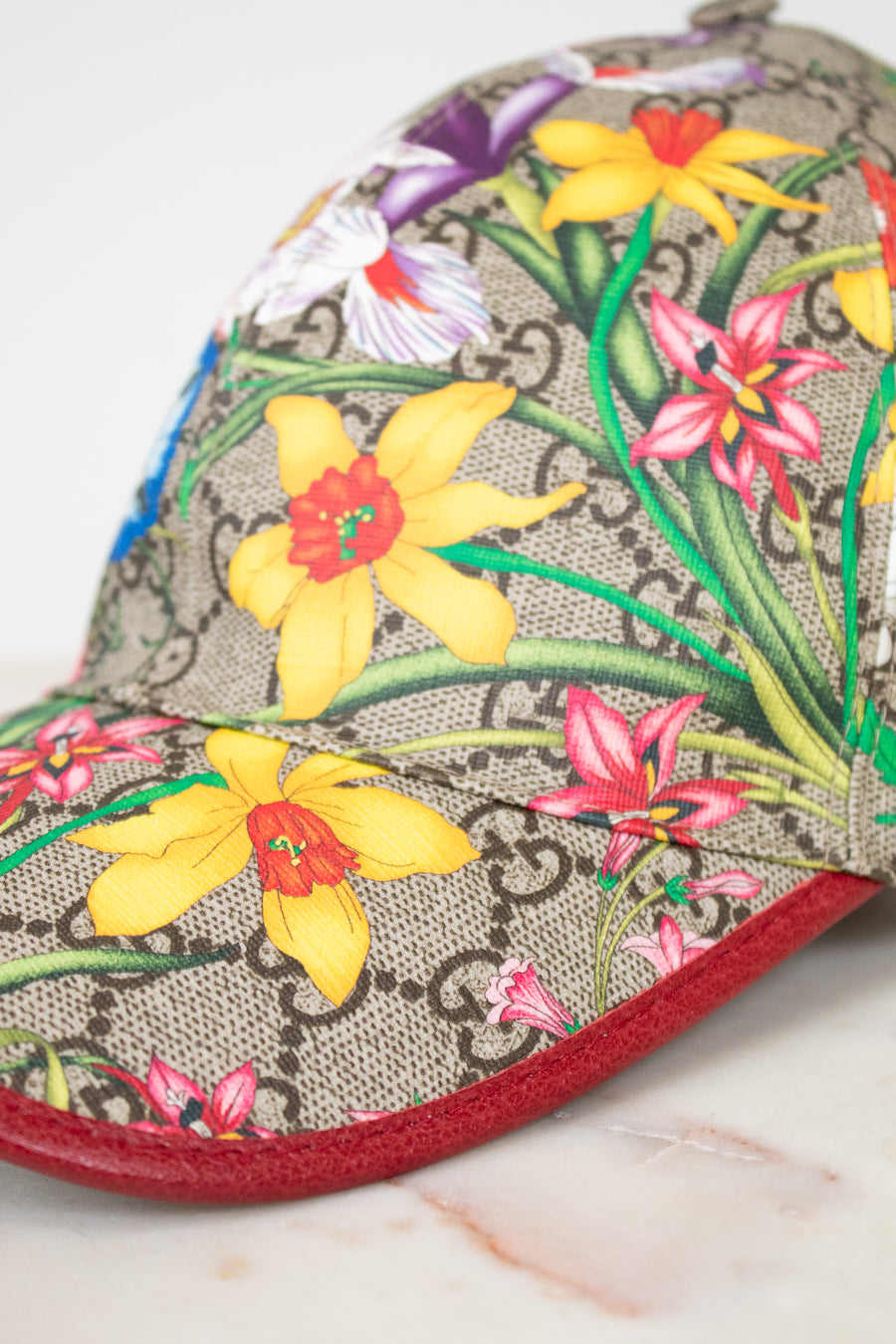 Floral-patterned cap with a red brim on a marble surface