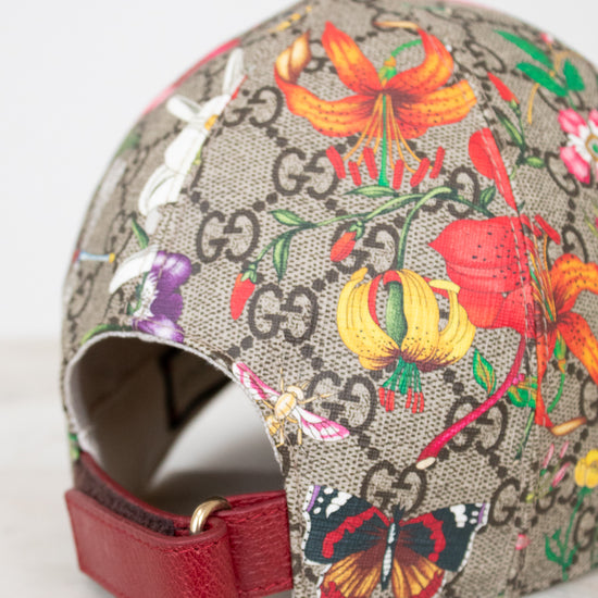 Colorful floral and butterfly patterned cap with Gucci logo on a light gray background