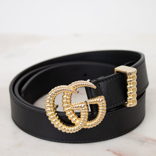 Black belt with a gold GG logo buckle on a marble surface