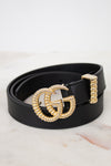Black belt with a gold GG logo buckle on a marble surface